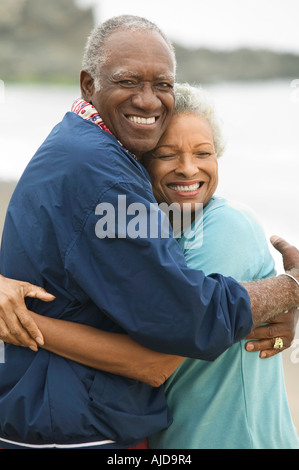 Älteres paar umarmt am Strand Stockfoto