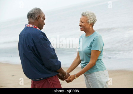 Älteres Paar halten die Hände am Strand Stockfoto