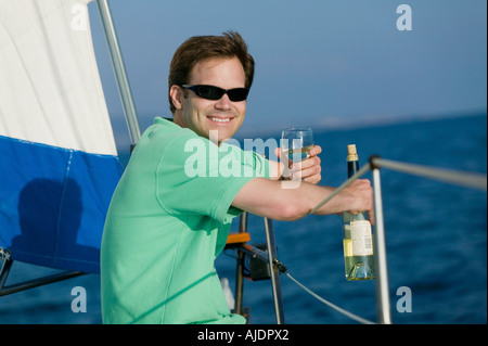 Mann sitzt auf Segelboot, weißen Wein trinken, (Portrait) Stockfoto