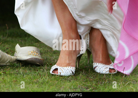 Eine Braut ändern ihre Schuhe ausziehen Stilettos für bequemere Schuhe für Spaziergänge in Stockfoto