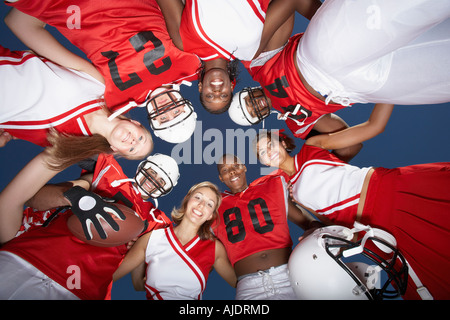 Football-Spieler und Cheerleader im Huddle, Ansicht von unten (Ansicht von unten) Stockfoto