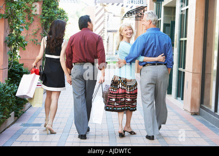 Mittleren Alters Paare gehen, Hand in Hand, umarmt auf Shopping Reise, Ansicht von hinten Stockfoto