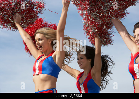 Cheerleader mit Pom Poms in der Luft halten Stockfoto