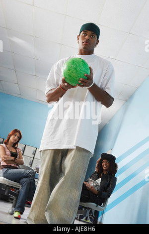 Junger Mann auf Bowling-Bahn hält, Kugel, Porträt, niedrigen Winkel Ansicht Stockfoto