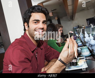 Junge Leute, die Sushi-Essen mit Stäbchen im restaurant Stockfoto