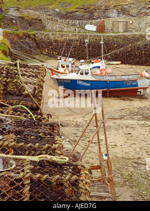 Krabben- und Hummertöpfe auf Quayside, Fischerboote, die im Boscastle Harbour am Tiefwasser Boscastle Cornwall England Großbritannien angelehnt sind Stockfoto