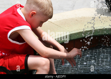 Ein kleiner Junge in einem Brunnen in der Hitze des Sommers Abkühlung Stockfoto