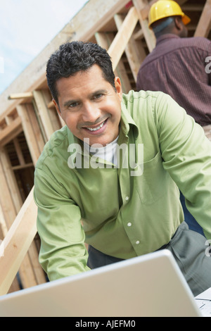 Lächelnde Bau Arbeiter mittels Laptop auf Bau Website Stockfoto