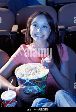 Lächelnde junge Frau essen Popcorn, beobachtete Film im Theater Stockfoto