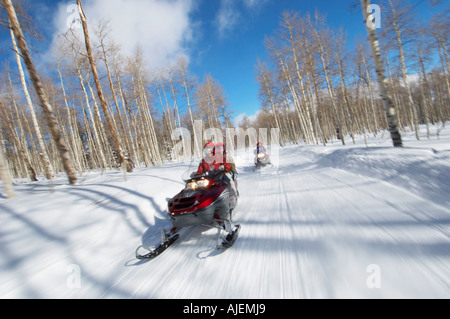 Zwei Paare Reiten auf zwei Motorschlitten auf verschneiter Piste Stockfoto