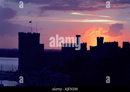 Caernarfon Castle mit walisische Flagge und Boote gegen dramatischen Sonnenuntergang Stockfoto