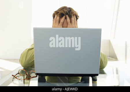 Gestressten Geschäftsmann mit Laptop im Büro Stockfoto