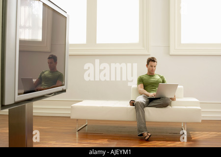 Mann mit Laptop auf modernes Sofa in modernen Wohnung Stockfoto