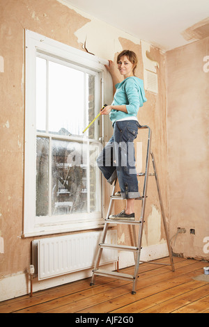 Frau stehend auf Trittleiter in unrenovierten Zimmer Stockfoto