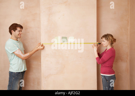 Paar Holding Maßband an der Wand in unrenovierten Zimmer Stockfoto