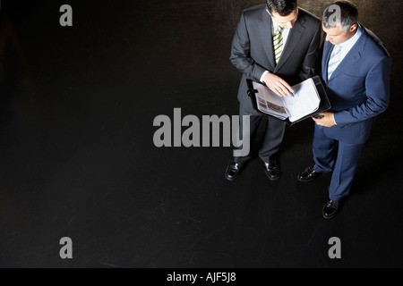 Erhöhten Blick auf zwei Geschäftsleute Lesen von Dokumenten vor einem dunklen Hintergrund Stockfoto