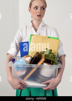 Büroangestellte, die persönliche Gegenstände in einer Kiste tragen und