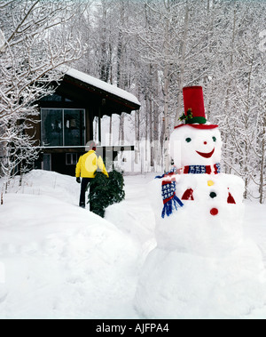 Der Weihnachtsbaum nach Hause zu bringen, mit schwungvollen Schneemann Dinge im Auge behalten Stockfoto