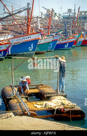 Rayong Thailand Ban Phe Hafen vertäute Schiffe und 2 Fischer arbeiten und von einer schwimmenden Floß Trommel aus Holz und Metall Stockfoto