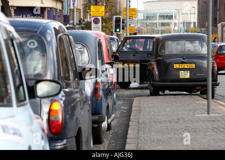 Taxi verlassen vor der Taxistand mit Reihe von London Stil Mietpferd Wagen Taxis aufgereiht in Belfast City Centre Stockfoto