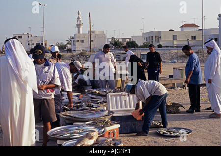 Arabische Männer in traditioneller Kleidung plus Frau in Burka kaufen Fisch Markt, Bahrain Stockfoto