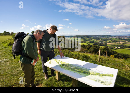 Zwei Wanderer auf dem Cotswold Weg genießen den Blick über den Severn Vale aus Coaley Peak Picknickplatz, Gloucestershire Stockfoto