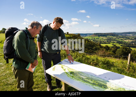 Zwei Wanderer unterwegs genießen den Blick über den Severn Vale aus Coaley Peak Picknick Website Gloucestershire Cotswold Stockfoto