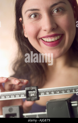 Kaukasische junge Frau angenehm überrascht, wenn Sie ihr Gewicht auf die Waage überprüft Stockfoto