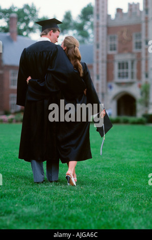 Kaukasische männlichen und weiblichen Absolventen zu Fuß über den Rasen zu umarmen Stockfoto