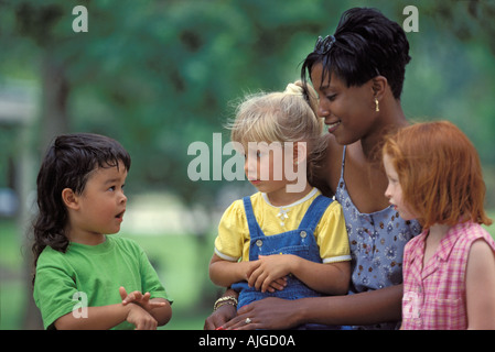 Afrikanische amerikanische Lehrer mit kaukasischen und Asiatischen Vorschule draußen sitzen in der Pause Stockfoto