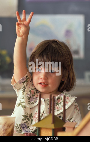 Porträt Caucassian Studentin Erhöhung Hand in Vorschulklasse Stockfoto