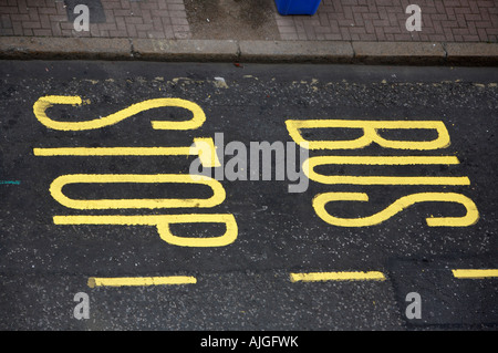 Bushaltestelle in leuchtend gelben Farbe auf Asphalt auf der Straße im Stadtzentrum von Belfast lackiert Stockfoto