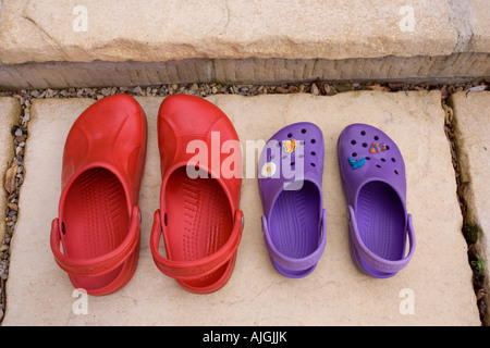 Paar rote adult Croc Sandalen und lila Kind Sandalen auf Schritt vor Tür UK Stockfoto