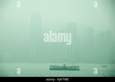 Die Star Ferry Kreuze, die Victoria Harbour in Smog mit der Skyline von Hong Kong hinter gehüllt. Stockfoto