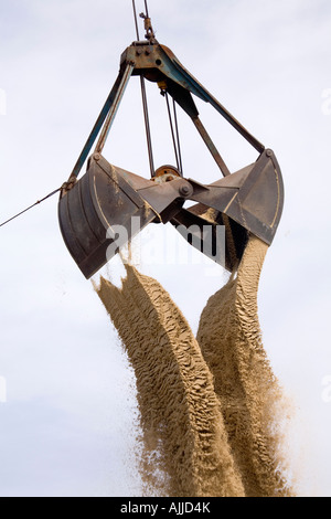 Ein Klapphandy Bucketloader ist dumping Sand vor blauem Himmel mit leichten Wolken gesehen. Stockfoto