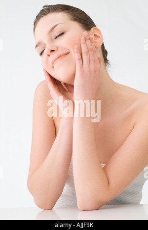 Junge Frau, die ihr über die Wangen zu berühren Stockfoto
