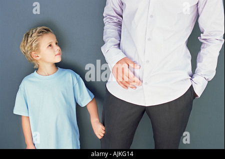 Junge in des Vaters Hosenbein ziehen Stockfoto