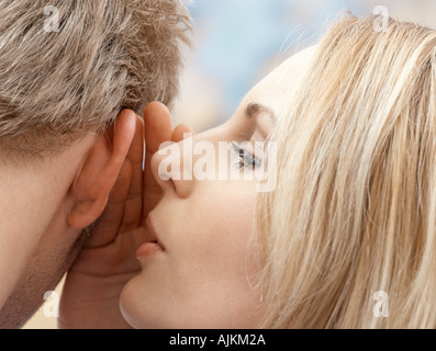 Frau des Mannes ins Ohr flüstern Stockfoto