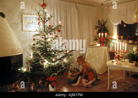 Jungen und Mädchen mit Geschenke unter dem Weihnachtsbaum in Kerze beleuchtet skandinavischen Heimat Stockfoto