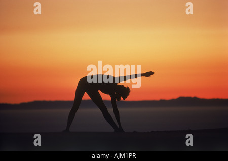 Frau, die Ausübung auf Hügel in der Abenddämmerung über Horizont abhebt Stockfoto