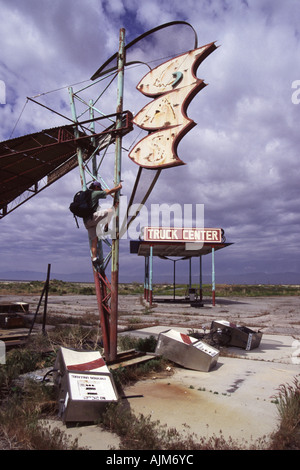 Ein Mann, eine alte Truck Stop-Schild in der Wüste in der Nähe von Bonnevile Salt Flats UT Klettern Stockfoto