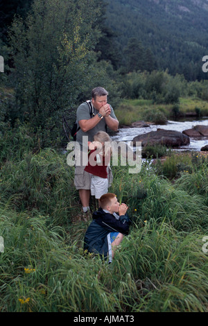 Vater Kinder spielen Pfeifen Spiel mit Grashalmen Moraine Park Rocky Mtn Nat l Park CO Stockfoto