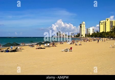 San Juan Puerto Rico Isla Verde Beach mit Sonnenanbeter, blauen Himmel und Resort Hotels im Hintergrund, Plam Bäume säumen Strand Stockfoto