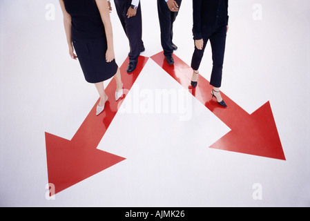 Vier Personen zu Fuß entlang Pfeil-Zeichen Stockfoto