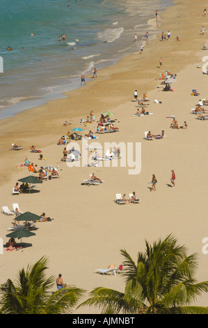 San Juan Puerto Rico Isla Verde beach mit Sonnenanbeter, blauer Himmel und Resort-Hotels im Hintergrund, Plam Bäume säumen Strand, Antenne Stockfoto