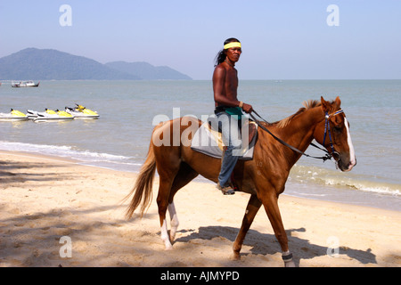 Eine Mann bietet Ausritte am Strand von Batu Ferringhi, Insel Penang, Malaysia. Stockfoto