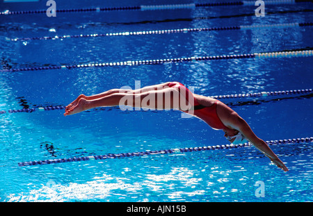 Ein Frau Schwimmer taucht in racing Bahnen an einem sonnigen Tag Stockfoto