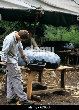 CORACLE BUILDING-Kurs Student Kattun Baumwollstoff mit schwarzer bituminöse Farbe malen, Boot zu imprägnieren. England-UK Stockfoto