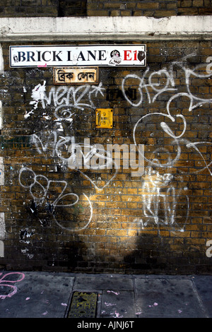 Eine Straße Zeichen der Brick Lane in Englisch und Bengali auf einem geritten Graffitiwand in Brick Lane East London Vereinigtes Königreich Stockfoto