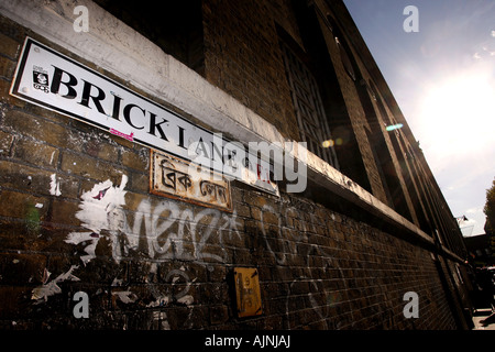 Eine Straße Zeichen der Brick Lane in Englisch und Bengali auf einem geritten Graffitiwand in Brick Lane East London Vereinigtes Königreich Stockfoto